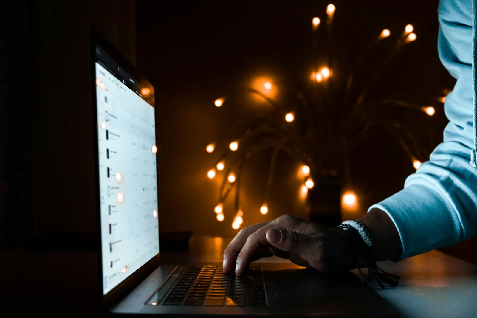 Person using a laptop in a dark room lit by the screen