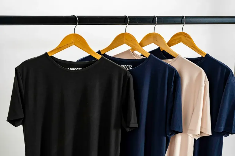 Plain T-shirts in several colours hanging on a clothing rail