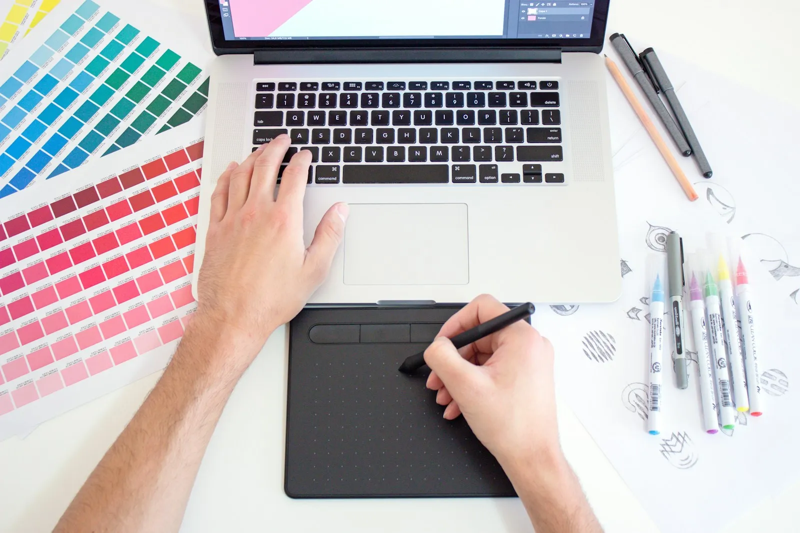 Designer working with a drawing tablet, laptop and colour swatches
